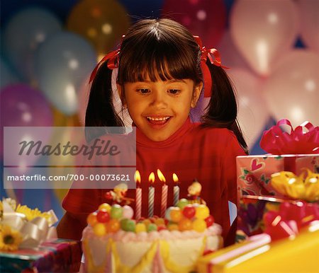 Girl Sitting at Table with Birthday Cake and Gifts