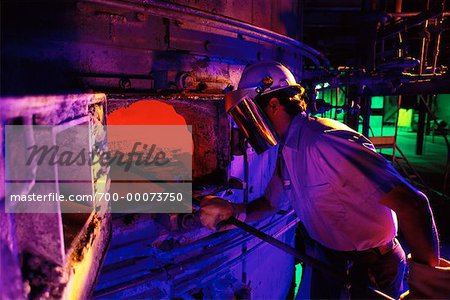 Worker Putting Rod in Industrial Furnace