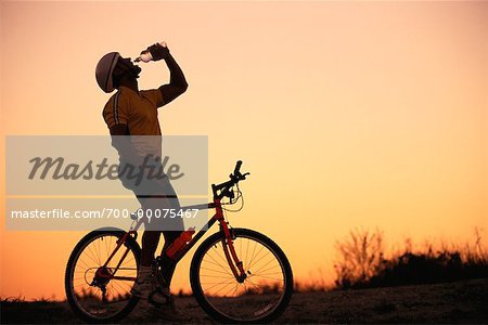 Man on Mountain Bike, Drinking Water at Sunset