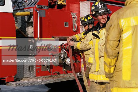 Male Firefighters Connecting Hose to Fire Truck