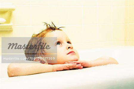 Garçon se penchant sur le bord de la baignoire