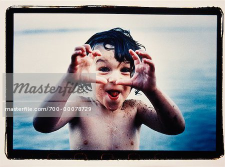Portrait d'enfant debout dans l'eau, rendant le visage et le geste de la main
