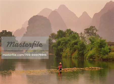 Man Sitting on Rocks in Yulong River by Dragon Bridge, near Yangshuo, Guangxi Region, China