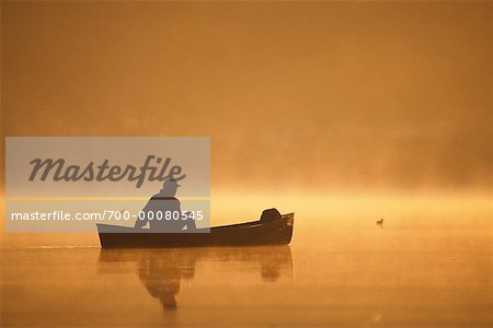 Ältere Mann Angeln von Canoe bei Sonnenaufgang