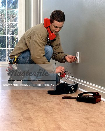 Male Technician Installing Telephone Line in Home