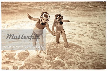 Deux jeunes filles en maillot de bain, porter des lunettes de protection, main dans la main sur la plage, masque et tuba
