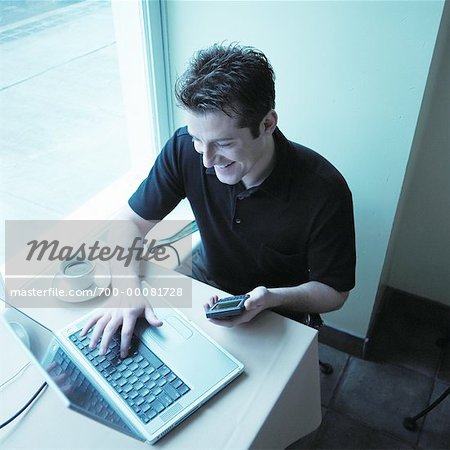 L'homme ordinateur portable à l'aide et organiseur électronique au café