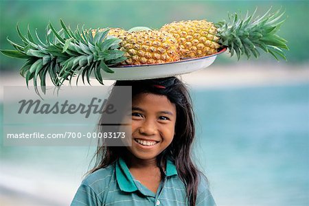 Porträt von Mädchen tragen Tablett mit Ananas auf Kopf, Senggigi Beach, Lombok, Indonesien