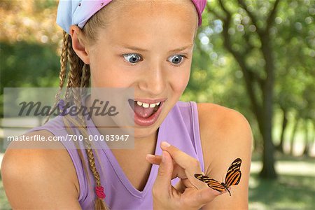 Girl Looking at Butterfly on Fingertip Outdoors