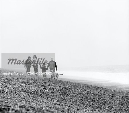 Family Walking on Beach with Dog England