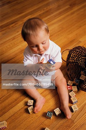 Child Sitting on Floor, Playing With Letter Blocks