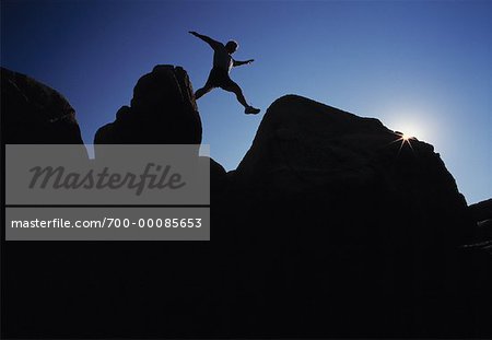 Silhouette der Mann über Felsen springen