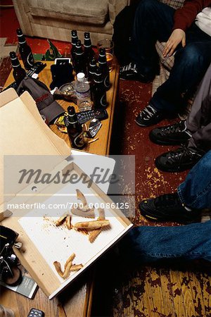 Group of People Sitting on Sofa With Beer Bottles and Pizza Box On Table with Messy Floor