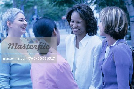 Four Women Standing Outdoors Laughing