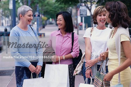 Quatre femmes debout tenant à l'extérieur des sacs à provisions