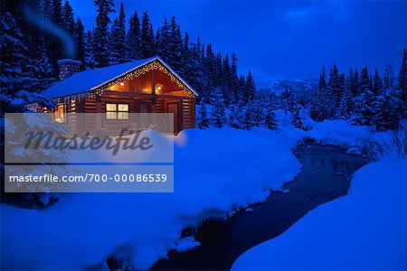 Log Cabin by Stream in Winter At Dusk