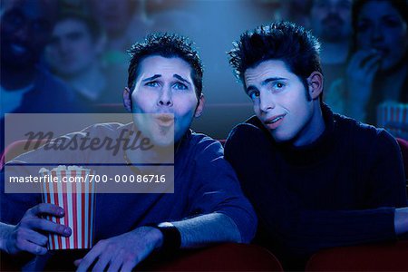 Deux jeunes hommes regarder film dans le théâtre