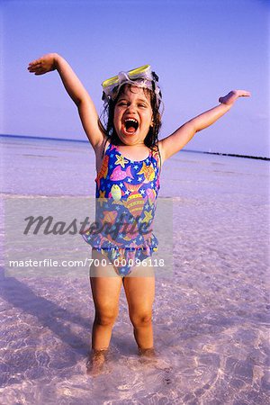 Young Girl Standing in Water With Arms in Air