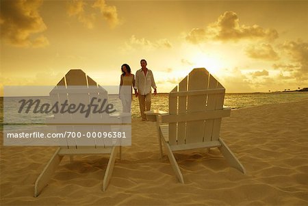 Couple on Beach Walking Toward Adirondack Chairs Paradise Island, Bahamas