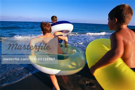 Kinder laufen am Strand mit Schläuche