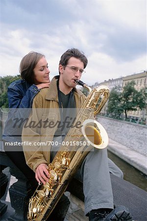 Jeune femme écoutant Young Man jouer Saxophone