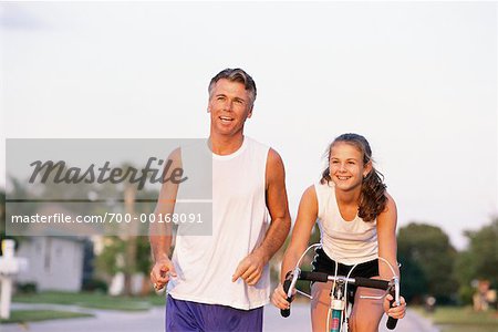 Père en cours d'exécution à côté de la fille sur le vélo