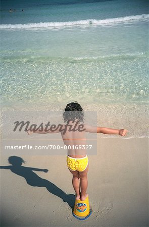 Child Standing on Bucket on Beach