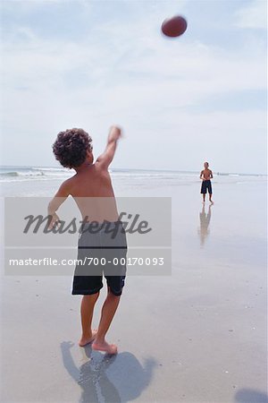 Garçons jouant attrapent sur la plage
