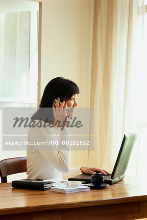 Businesswoman on Cell Phone Sitting at Desk with Laptop Paris, France