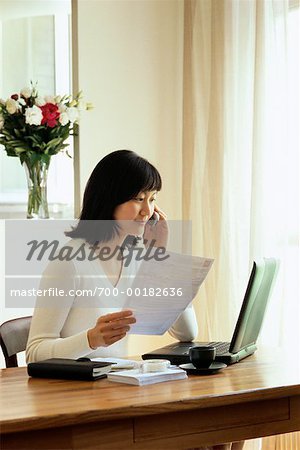 Businessswoman sur téléphone portable assis au bureau avec ordinateur portable