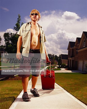 Homme avec des bagages sur le trottoir de banlieue