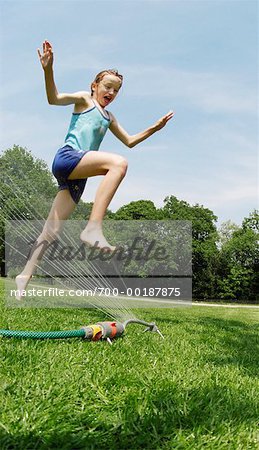 Girl Jumping Over Sprinkler