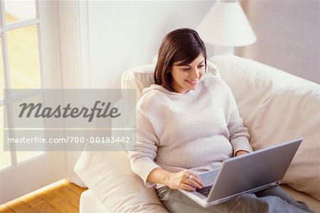 Femme sur le canapé à l'aide d'ordinateur portable