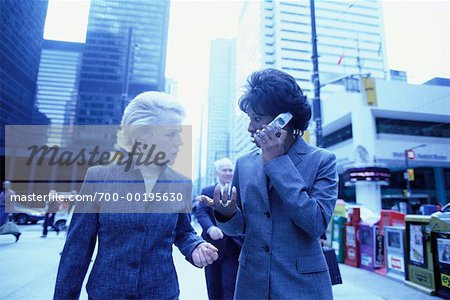 Femmes d'affaires avec téléphone cellulaire sur le trottoir