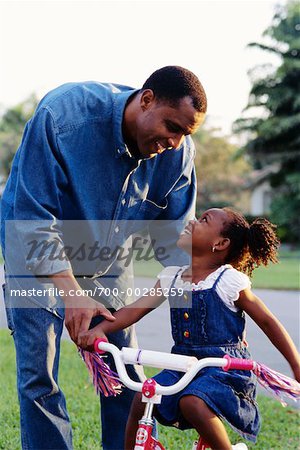 Father Helping Daughter to Ride A Bike