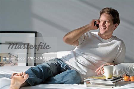 Man Using Cell Phone on Bed