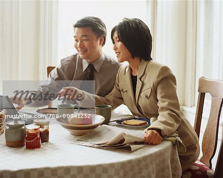 Couple à la recherche à l'ordinateur portable et le petit déjeuner