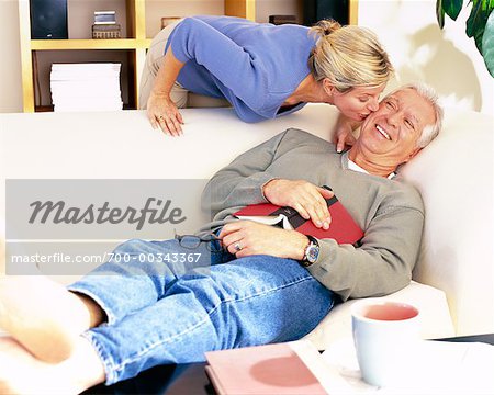 Man Resting on Sofa and Woman Kissing Him on Cheek