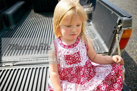 Child Sitting in Truck, Looking Sad