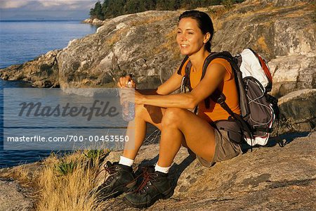 Frau sitzt am Felsenufer