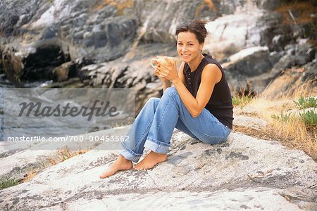 Frau sitzt auf den Felsen mit Kaffee