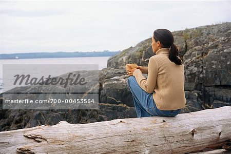 Woman Sitting on Log with Coffee