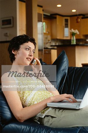 Femme à l'aide d'ordinateur portable, parler au téléphone cellulaire