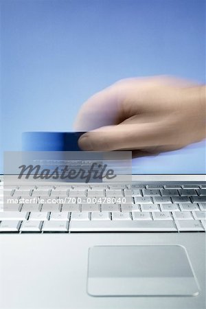 Hand Swiping Credit Card On Computer Keyboard