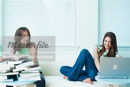 Portrait of Two Women, One Reading Books, One Using Laptop Computer