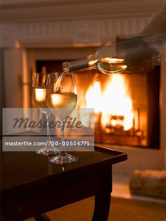 Pouring Glasses of Wine by Fireplace