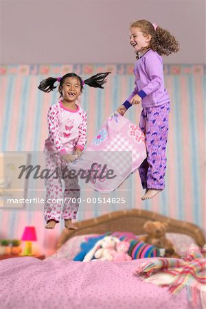 Zwei Mädchen bei einem Sleepover, springen auf dem Bett