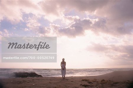 Femme debout sur la plage au crépuscule