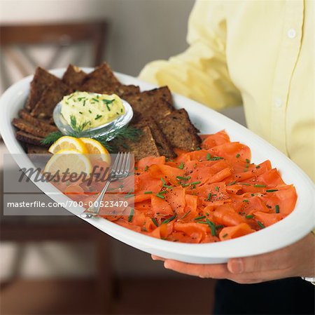 Man Holding Plate With Smoked Salmon, Pumpernickel Bread and Dill Cream Cheese