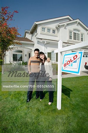 Couple debout par vendu signe en face de la maison, San Ramon, Californie, USA